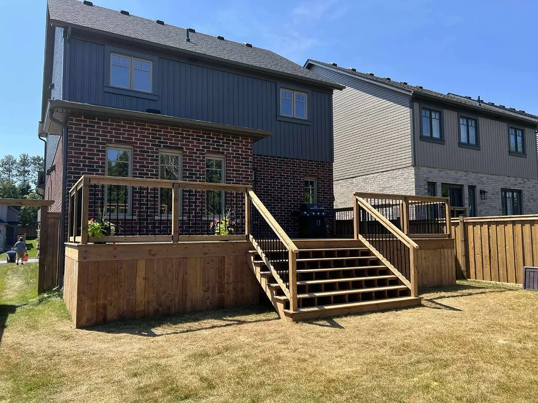 A finished two level deck with stairs across the back of a home
